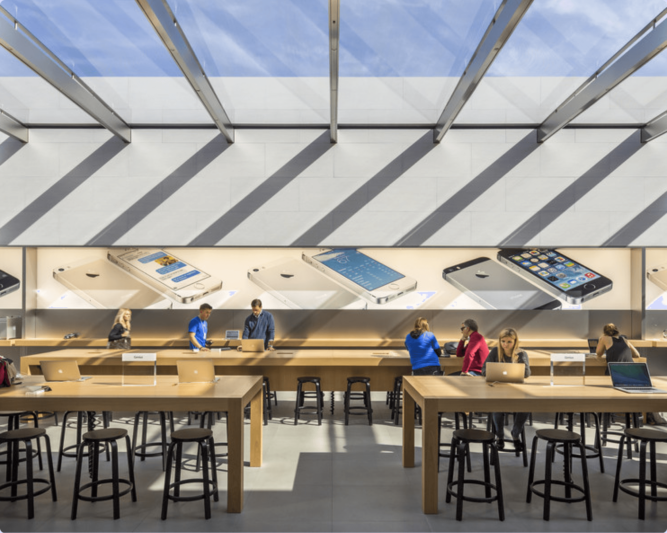 Interior of an Apple Store with wooden tables and a glass ceiling